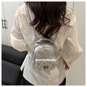 Detail of silver quilted mini backpack with chain straps worn on model back