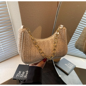 Détail du sac hobo en paille beige avec tissage chevrons et chaîne dorée épaisse