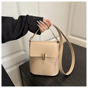Dettaglio di una borsa a secchiello beige con chiusura dorata e tracolla regolabile