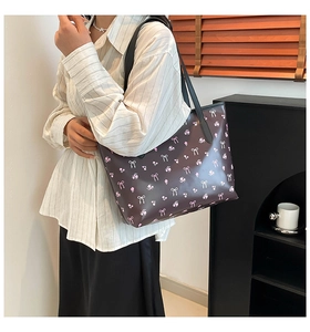 Detail view of large tote bag with pink floral and white bow pattern on dark brown base