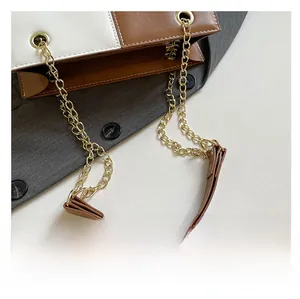 Detail of white and brown leather contrast bag with gold chain and shoulder pad
