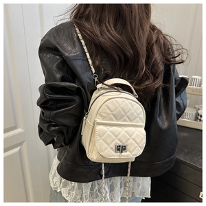 Quilted mini backpack in cream leather with chain straps worn by a model in interior