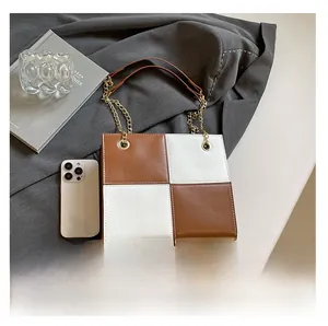 Detail of square crossbody bag with brown and white checkerboard pattern and gold chain strap