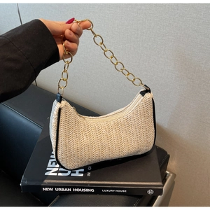Détail du sac baguette tissé avec poignée en chaîne dorée et motif à chevrons beige