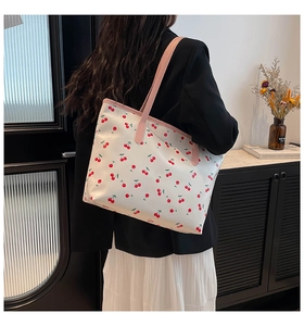 Detail of white tote bag with cherry print and pink leather straps on shoulder