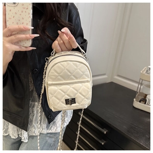 Close-up of beige quilted leather mini backpack with silver chain and metal turn-lock