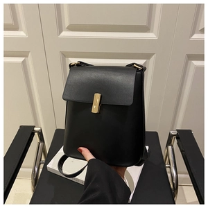 Dettaglio di borsa a tracolla nera minimalista con chiusura rettangolare in metallo dorato