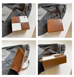 Detail view of square crossbody bag with brown and white color-block design and chain strap