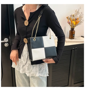 Detailed view of checkered black and white shoulder bag with gold chain strap detail