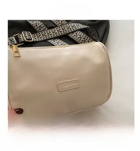 Detail of beige leather pillow bag featuring fashion tag and woven geometric strap