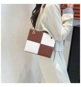 Detail of a brown and white checkered leather shoulder bag with a gold chain strap