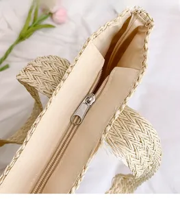 Detail of silver metal zipper and beige lining on handmade woven straw tote bag