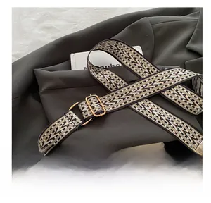 Detail of adjustable geometric woven shoulder strap with gold metal buckle and leather