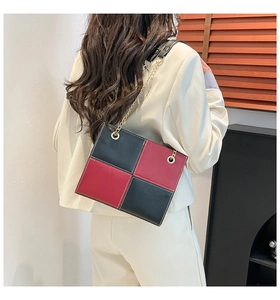 Detail of red and black color-block checkerboard chain bag on model's back