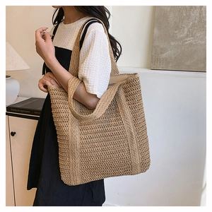 Detail of hand-woven straw tote bag showing the textured mesh pattern and shoulder strap