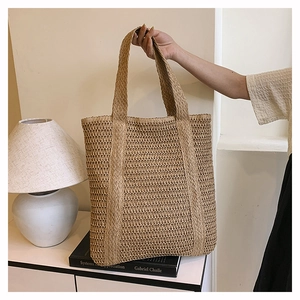 Close-up of a woven straw tote bag featuring detailed hollow-out craftsmanship and dual handles