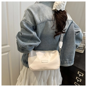 Detail of off-white crossbody pillow bag featuring a wide checkered strap and FASHION label