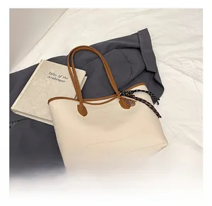 Detail of off-white tote bag featuring lychee grain texture and brown woven strap