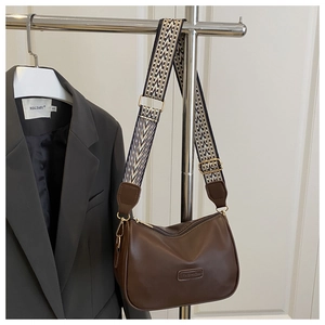 Detail of a brown PU leather pillow bag with a black and white geometric woven strap