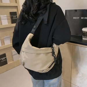 Minimalist beige crescent shoulder bag in durable nylon with wide black strap