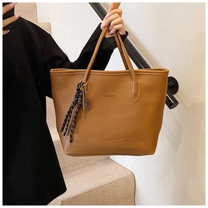 Detail of caramel tote bag with faux leather lychee texture and gold tennis racket charm