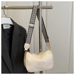Detail view of cream-white crescent bag featuring a stylish geometric woven shoulder strap