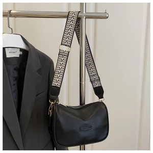 Detail of black leather handbag with FASHION emboss and geometric patterned wide strap