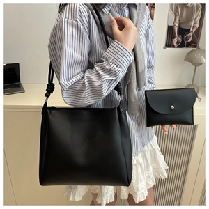 Detail of minimalist black tote bag set showing the knot design and silver hardware accent