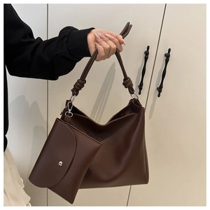 Detail of coffee brown PU leather bucket bag featuring a unique thick rope knot on the shoulder strap