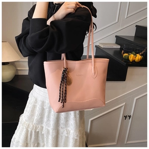 Detail of pink faux leather tote bag with FASHION text and decorative scarf charm