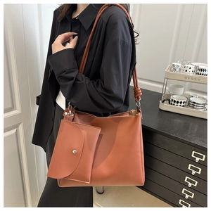 Close-up of caramel brown leather bucket bag with knotted straps and hanging pouch