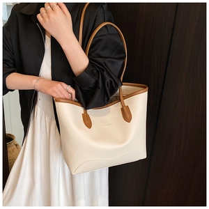 Close-up of cream tote bag with brown leather trim and embossed FASHION lettering