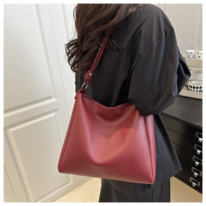 Detail of burgundy tote bag with knot strap on shoulder, minimalist 2025 summer commute style