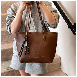 Detail of vintage brown pebble leather tote bag with tassels and shoulder strap on model