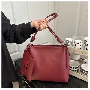 Detail of burgundy leather tote bag featuring a knotted handle and detachable inner pouch