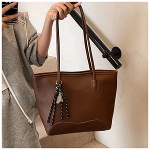 Detail of deep brown lychee grain leather tote bag with embossed fashion lettering