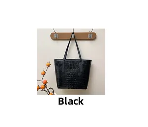 Close-up of black crocodile pattern tote bag hanging on a wooden hook in a cozy setting