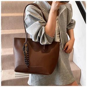 Detail of dark brown tote bag with FASHION logo and striped ribbon on leather