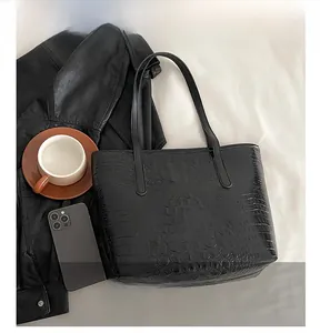 Detail of black faux crocodile leather tote bag with dual straps for daily commuting