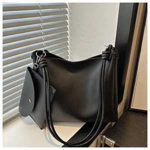 Detail shot of black leather tote bag with knot strap design and small inner pouch