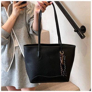 Detail of black litchi pattern tote bag with silk scarf charm and fashion embossing