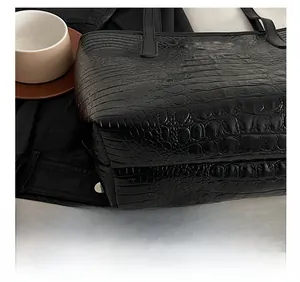 Detail shot of the precise stitching and crocodile texture on this black leather tote bag