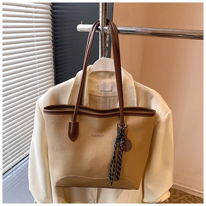 Detail of khaki pebbled leather tote bag with FASHION text and silk scarf accessory