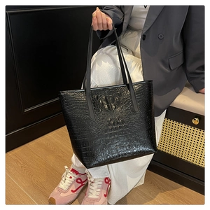 Close-up of black crocodile embossed leather tote featuring unique 3D animal relief detail