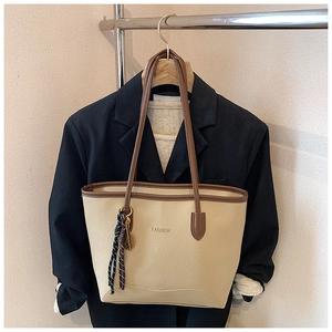 Detail of cream tote bag with brown handles and fashion logo on black blazer