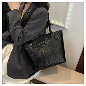 Fashionable black crocodile embossed tote bag styled with a gray suit for daily commute