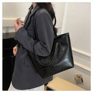 Close-up of black crocodile pattern leather tote bag with glossy finish and long handles