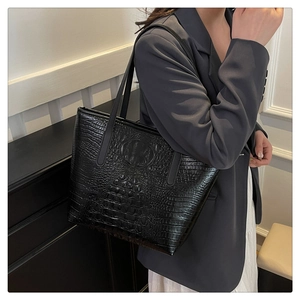 Detail of black crocodile texture tote bag with long shoulder strap in a minimalist style