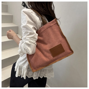 Outdoor side view of a large pink corduroy tote bag with brown trim for daily use