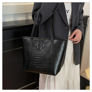 Detailed view of the glossy black crocodile embossed texture on a large tote bag